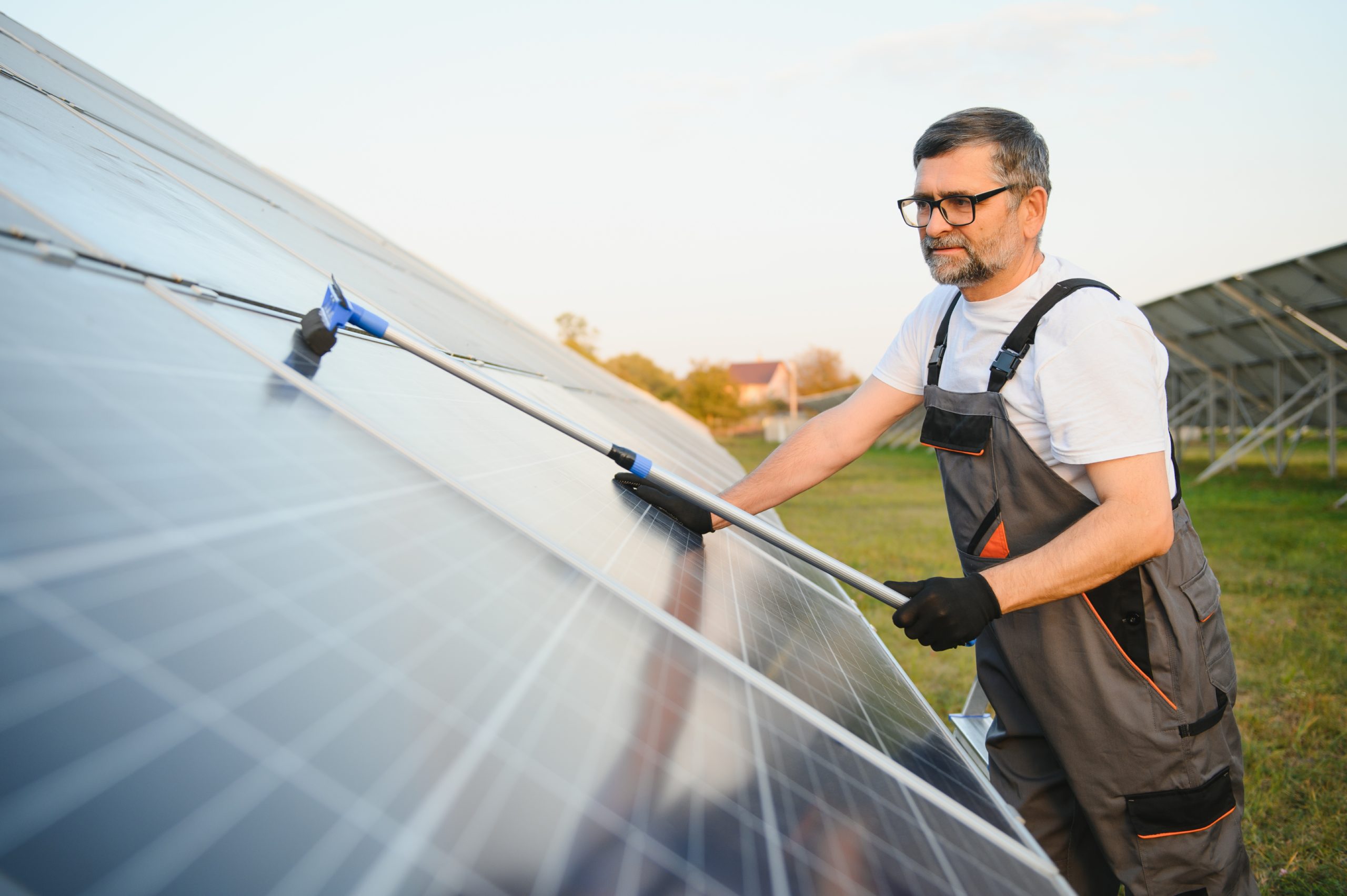 A handyman cleaning solar panels.